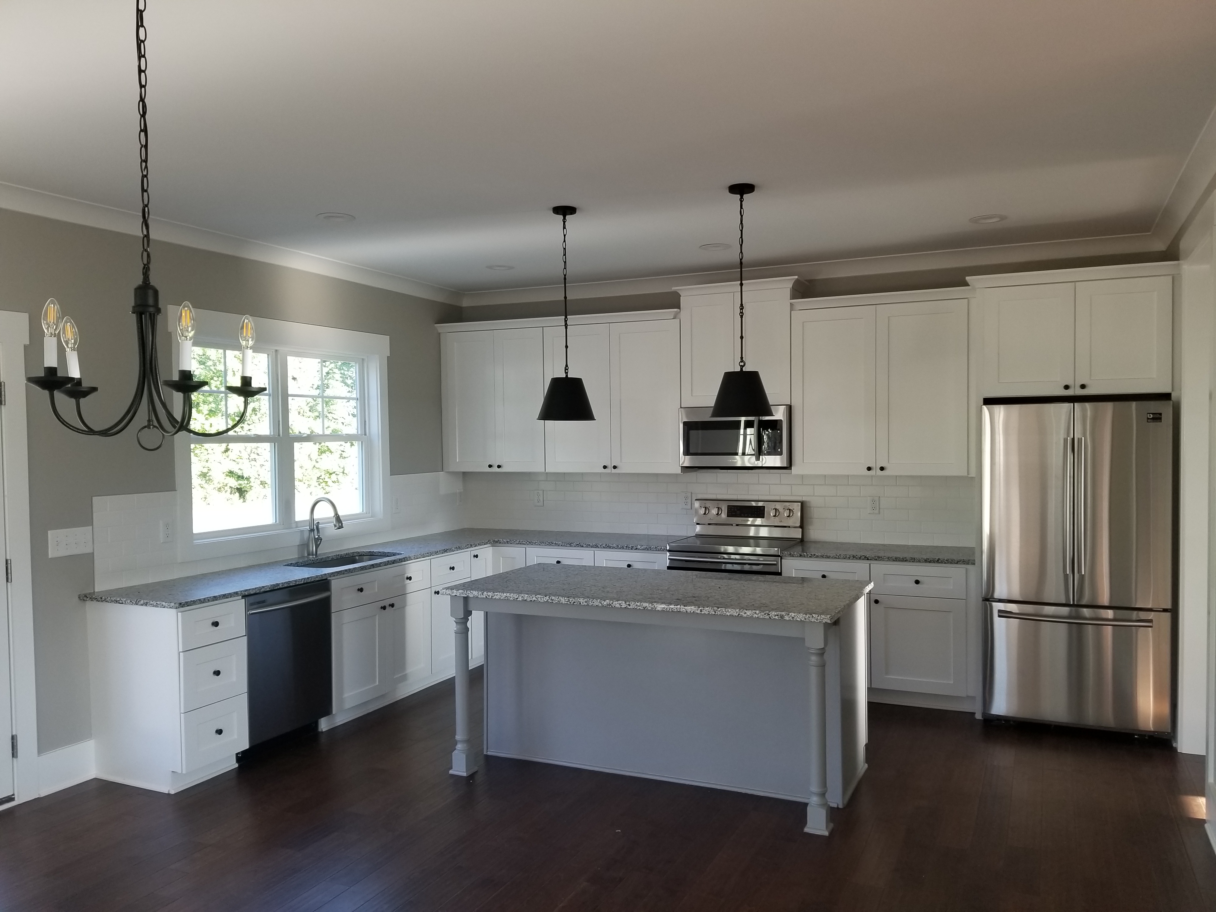 White updated kitchen with grey island and black pendant lights