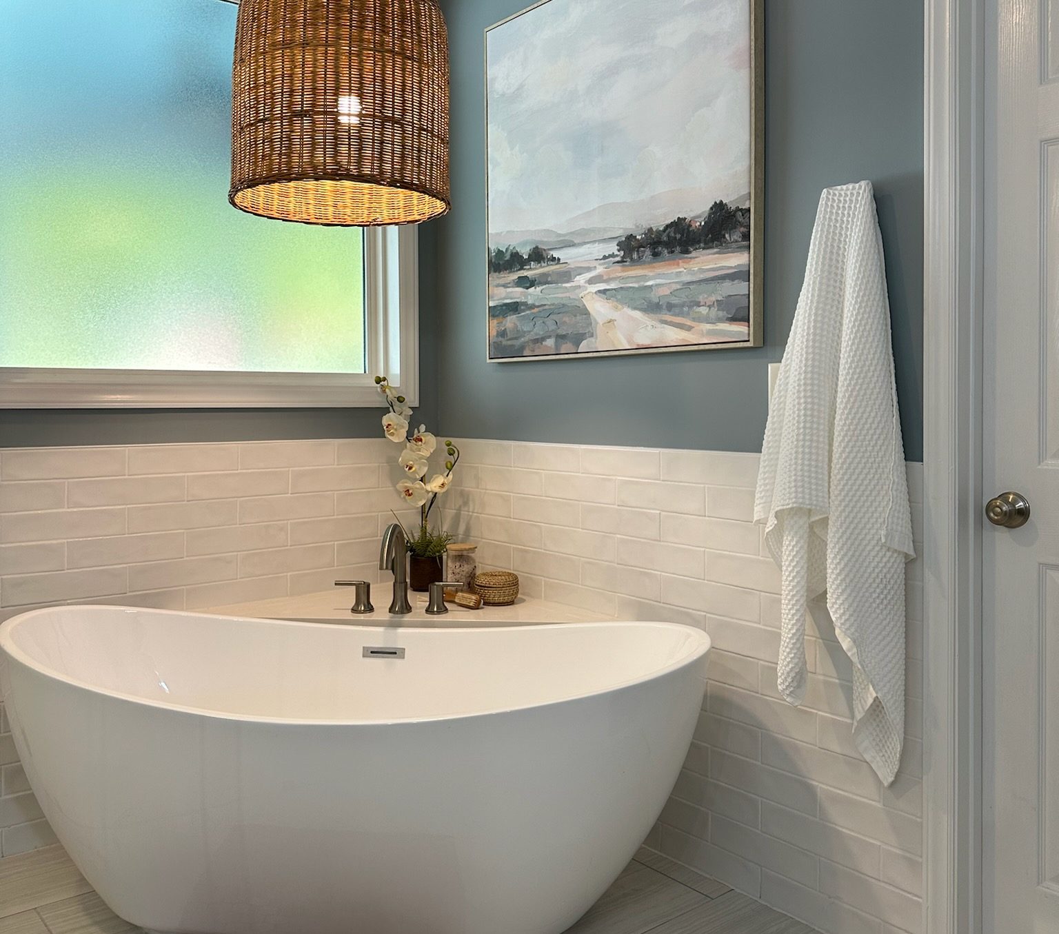 White stand alone tub with wicker light fixture above